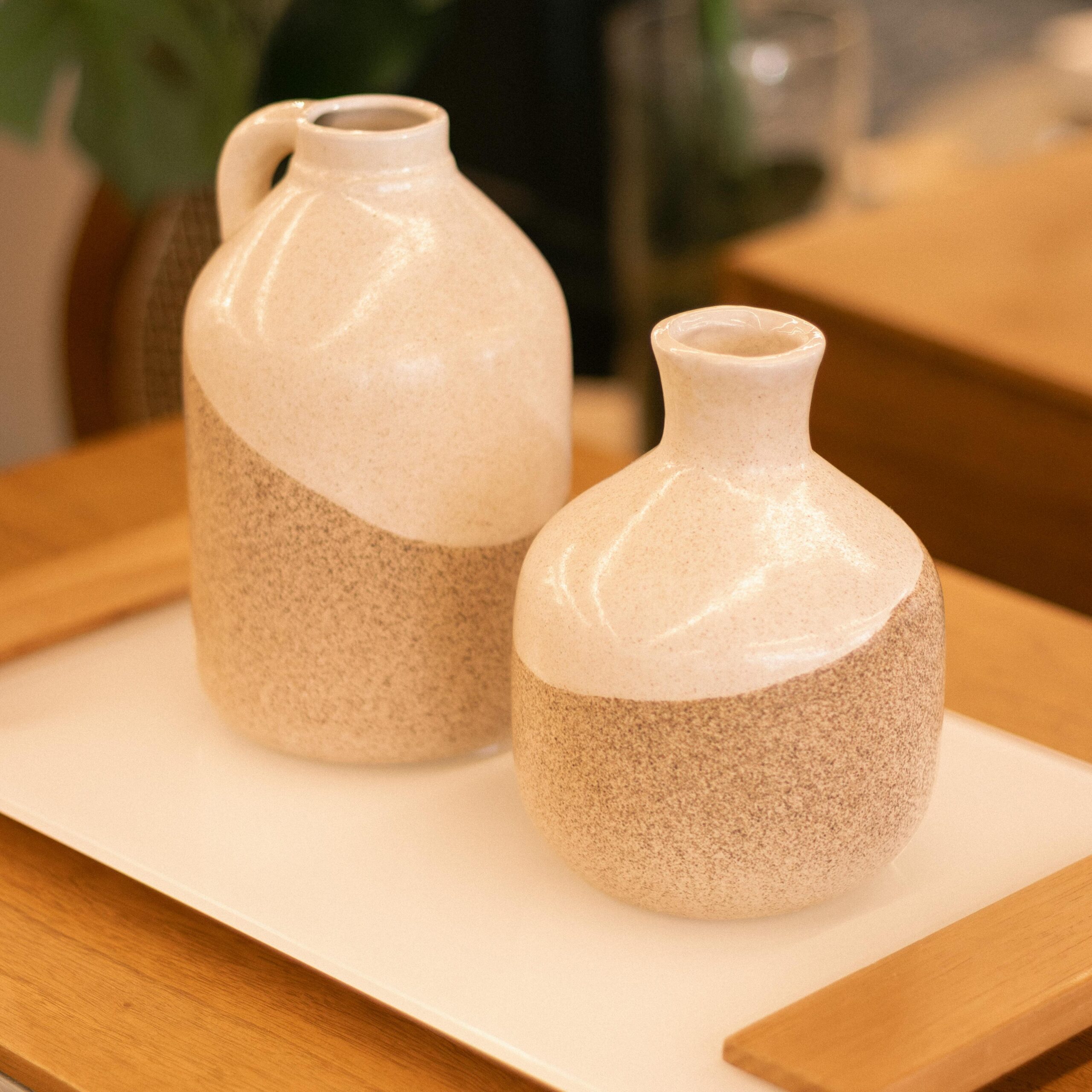 Two elegant ceramic vases on a wooden tray, showcasing minimalist decor.