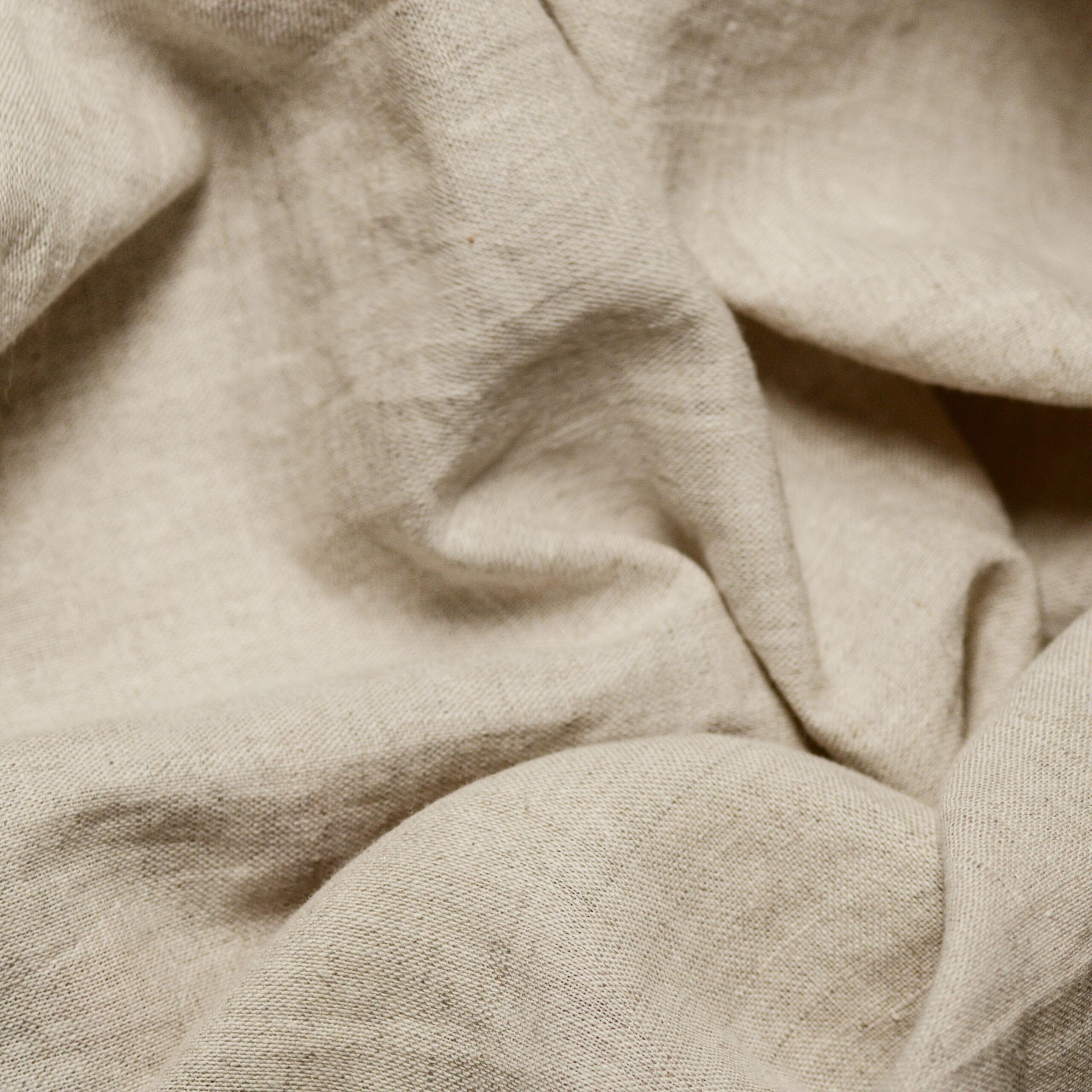 Close-up of beige cotton fabric showcasing natural texture and crumples.